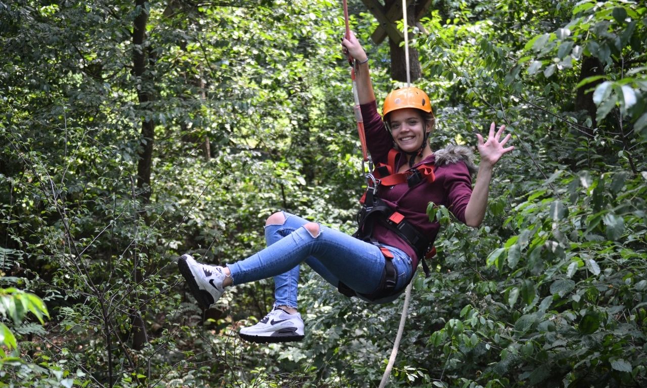 Frau bei Schnurstracks hängt in einer Zipline und winkt